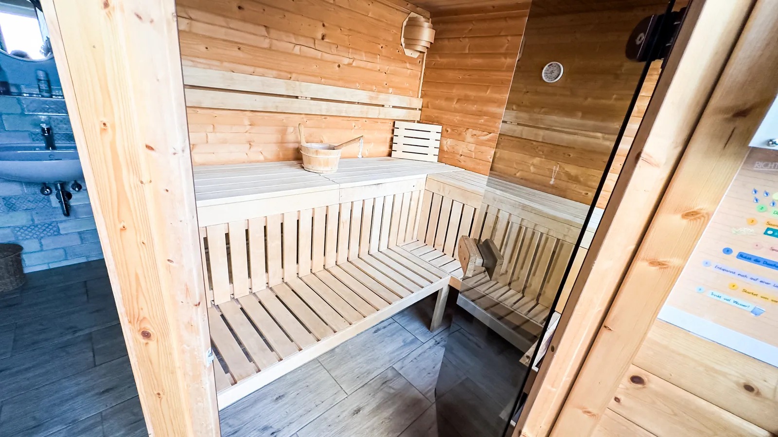 Finnish sauna in light wood with sauna bucket and thermometer