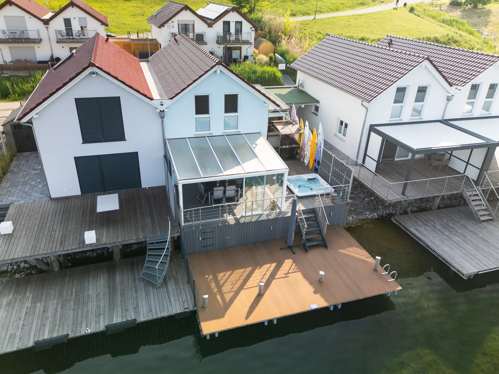 Aerial view: terrace with hot tub, paddle boards and large jetty right on the water